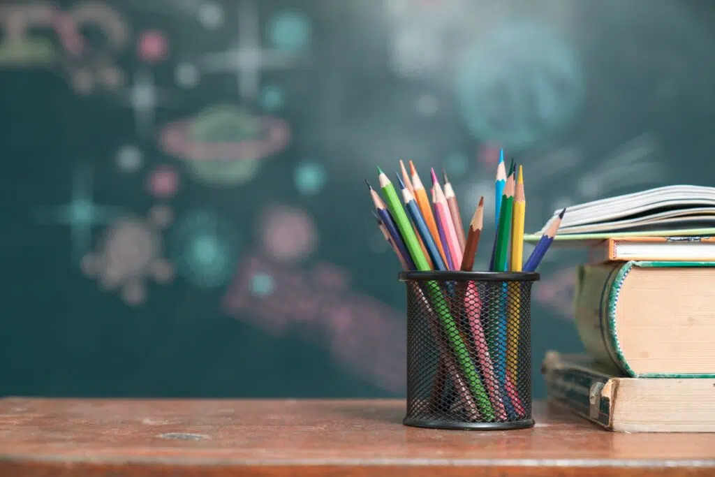 Coloured pencils in a lattice pot, and books on a desk